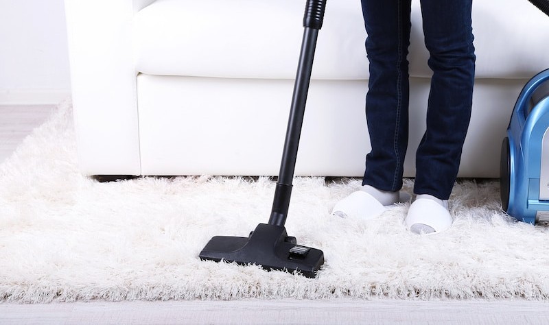 cropped picture of a person sprucing up a carpet with a vacuum cleaner