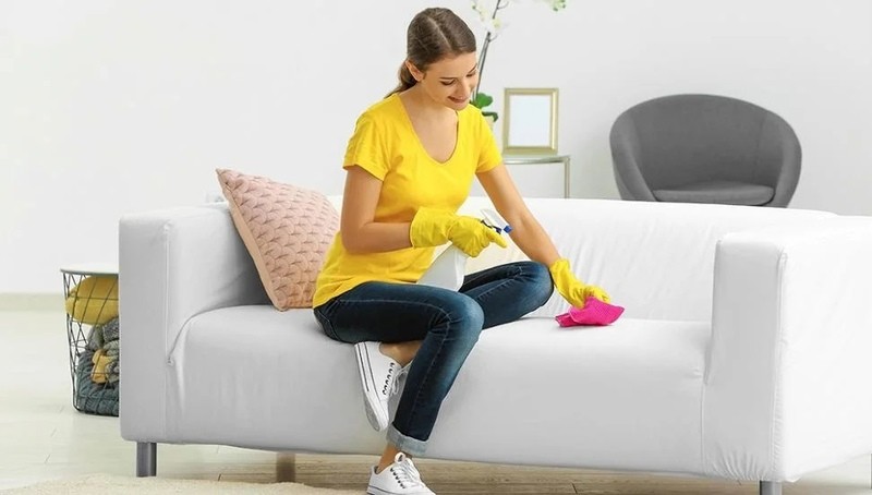 young woman disinfecting a couch