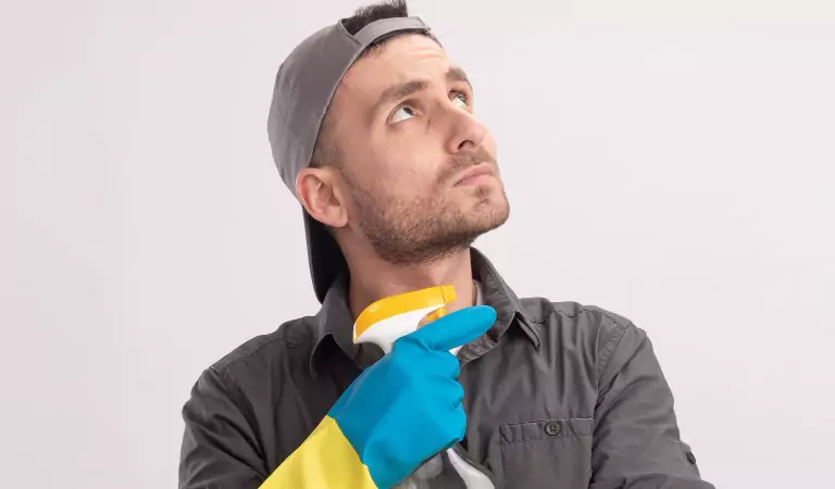 young man thinking about something and holding a cleaning spray