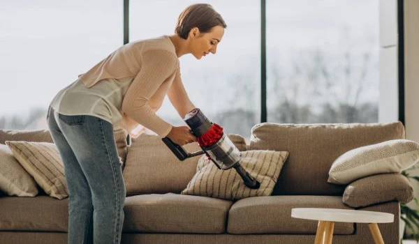Young woman with rechargeable vacuum cleaner cleaning at home