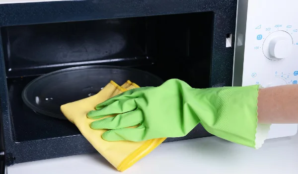 Cleaning microwave oven in kitchen closeup
