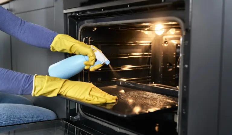 Close up of caucasian woman cleaning oven at home