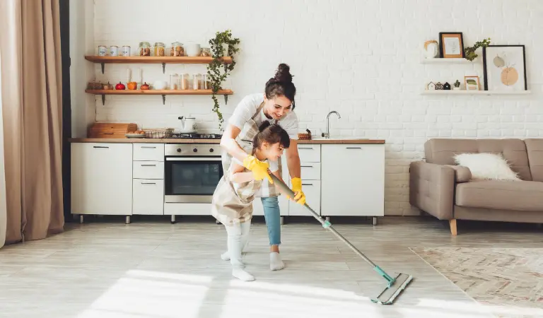 A little daughter and her mom clean the house a child washes the kitchen floor a cute little helper girl cleans the floor with a mop a happy family cleans the room