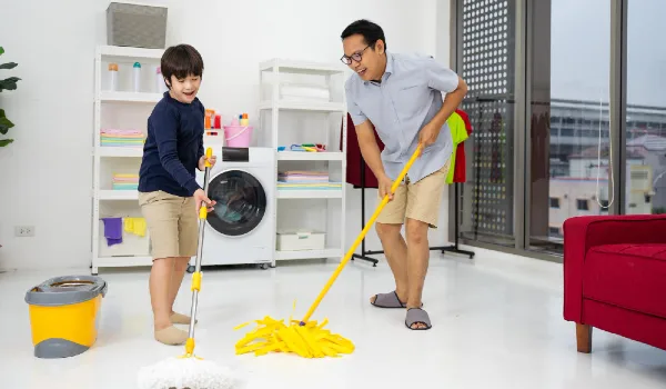 Happy family cleans the room. Asian father and son do the cleaning in the house. A young man and child girl are dusting, washing floor with towel and spray in living-room
