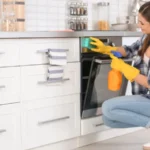 Young woman cleaning oven in kitchen